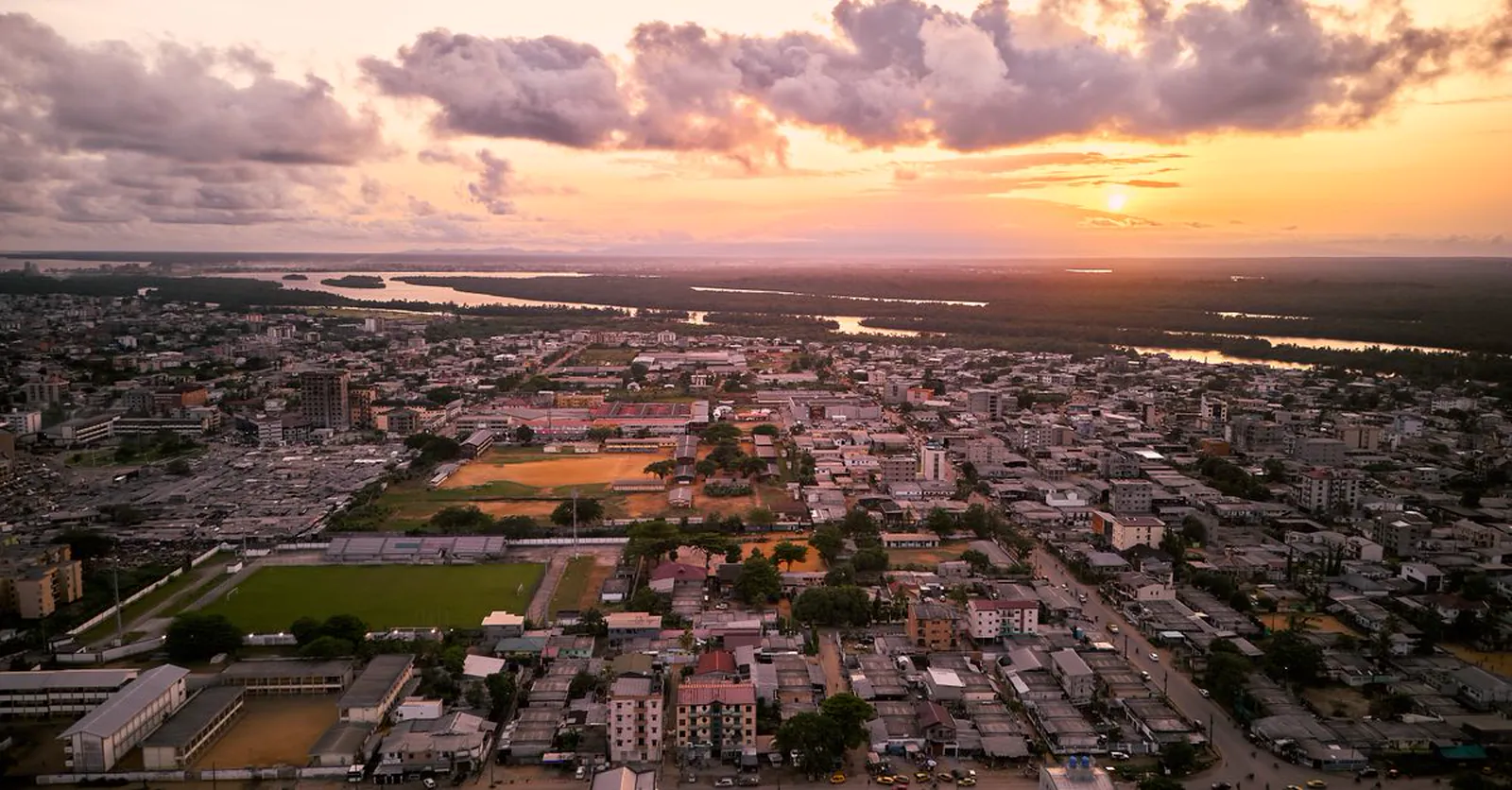 Vue aérienne de Douala au coucher du soleil, avec le tissu urbain et le port.